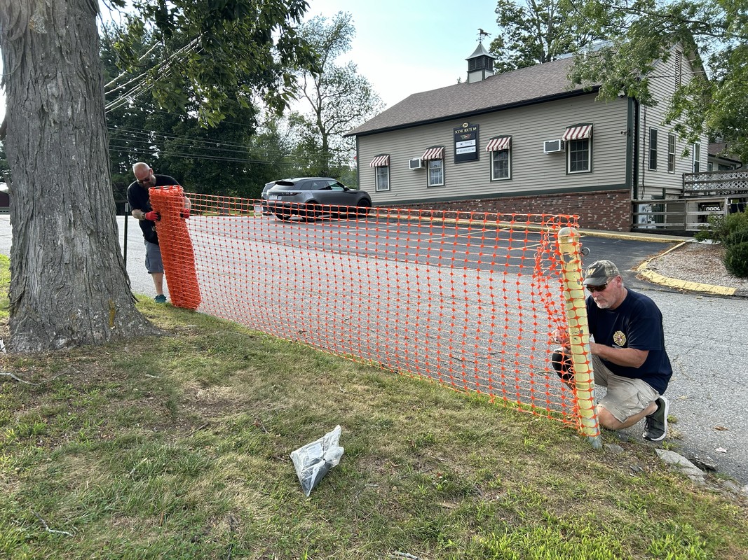 Two brothers installing orange fence around the lot.