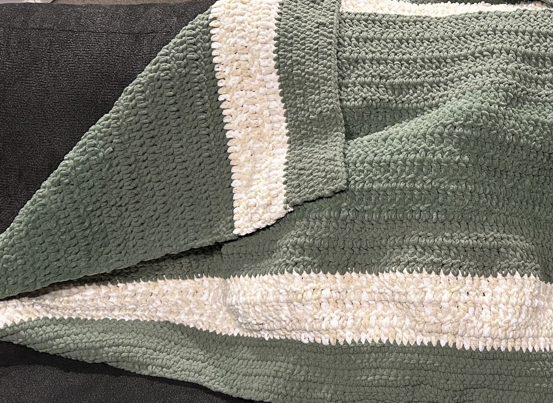 Image of a crochet baby blanket in green and white